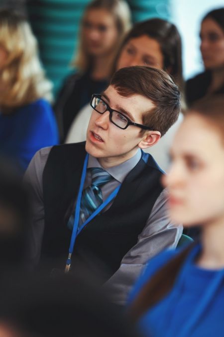 man in vest and tie in group of seated students