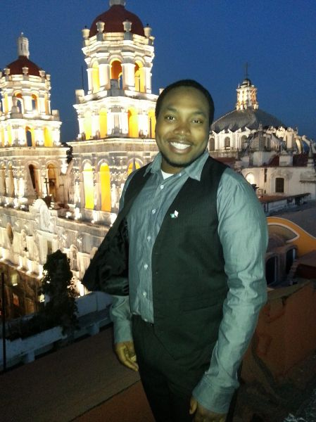 man in formal outfit standing in front of old building