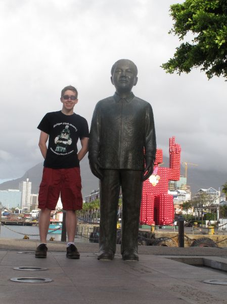 man standing next to tall statue of Nelson Mandela